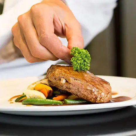 Sycamore Ridge Chef Created Meals, chef garnishing a plate.